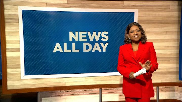 Ruschell Boone standing in front of a screen board with the words 'NEWS ALL DAY' as she is ready for a comeback.